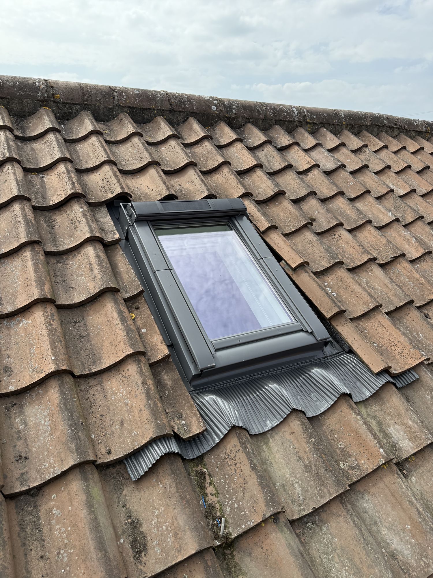 Clay tiled roof with a roof window and new flashing